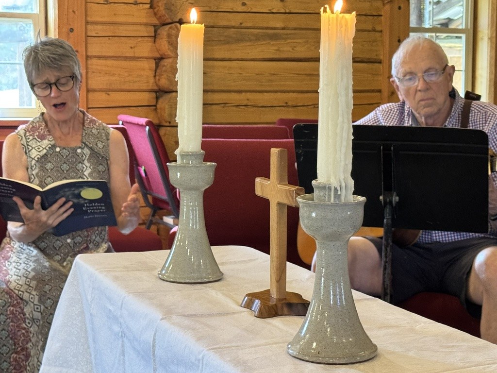 Singing evening prayer beside the altar candles and wooden cross in the log cabin church